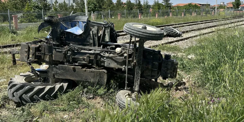 Trenin çarptığı traktör raylara devrildi
